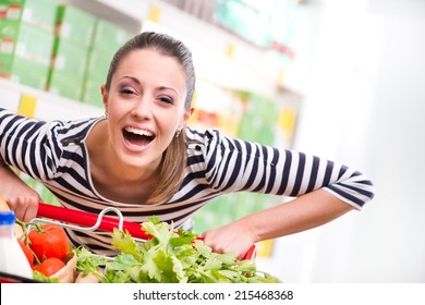 Attractive young woman smiling and pushing a cart at supermarket.