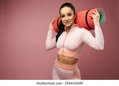 Attractive young woman in sportswear holding yoga mat - Powered by Shutterstock