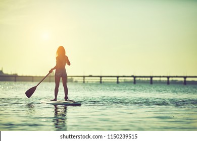 Attractive young woman stand up paddle surfing