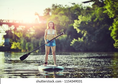 Attractive young woman stand up paddle surfing