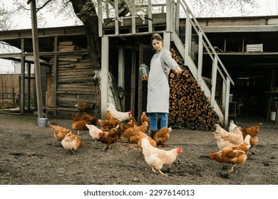 an attractive young woman standing near the chicken coop holding