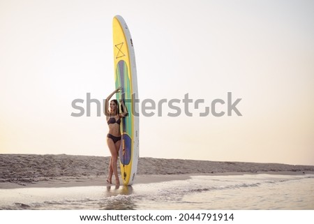 Similar – Young surfer woman with top and bikini holding surfboard