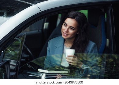 Attractive young woman taking a coffee break. Successful businesswoman with laptop, notebook and smartphone sitting in the car.