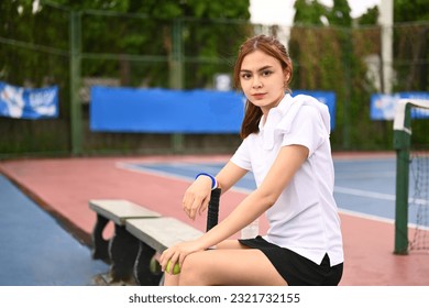 Attractive young woman tennis player resting on the bench at the tennis court after training - Powered by Shutterstock