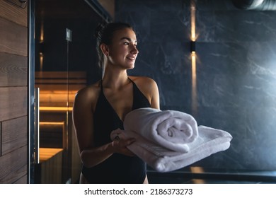 Attractive young woman with towels is relaxing in the sauna.