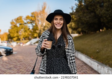 attractive young woman walking in autumn street wearing checkered black and white coat, black hat, happy mood, fashion style trend, black friday sale, sunny