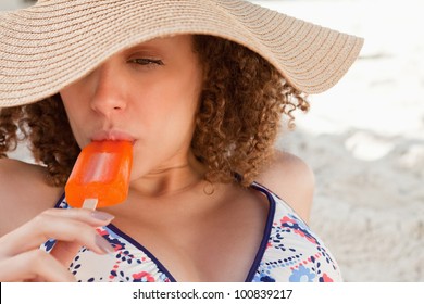 Attractive Young Woman Wearing A Straw Hat While Eating A Delicious Popsicle