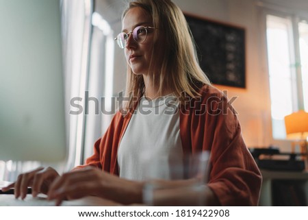 Attractive young woman working at modern office using computer typing text on keyboard looking at screen, Female customer assistant working remotely on computer answering customer enquiries