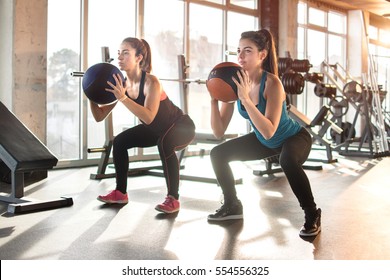 Attractive young women exercising with pilates ball at gym.