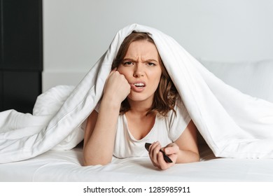 Attractive yupset oung woman lying in bed at home watching TV - Shutterstock ID 1285985911
