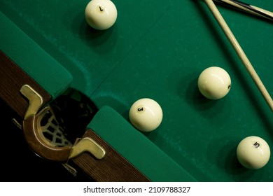 
Attributes for playing billiards. Billiard balls, cues and cue ball lie on the game green table near the pocket.