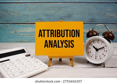 Attribution Analysis text written on paper card with calculator and alarm clock on wooden background