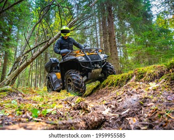 ATV with driver front view. He drives off-road in the forest. Offroad travel adventure trip expedition. Extreme recreation activity on an ATV. Travel on a yellow ATV. Man posing on a quad bike