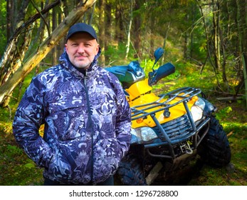 ATV. A man travels through the forest. SUV in the forest. All-terrain vehicle. Kvadro Motorcycle. Mature male traveler. Entertainment in nature. Yellow ATV. Off road travel. - Powered by Shutterstock