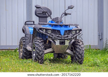 The ATV is parked near the house on a summer day