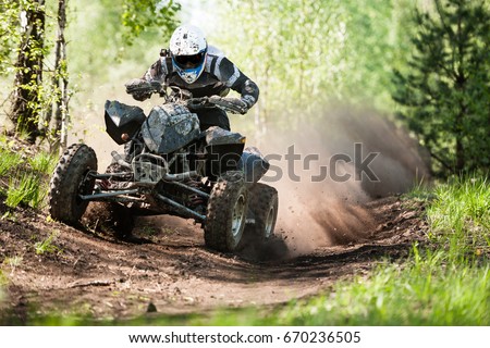 ATV rider creates a large cloud of dust and debris on sunny day