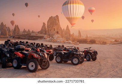 ATV trip quad bike in Cappadocia with set colorful hot air balloon fly in sky with sunset. Concept tourist travel Goreme Turkey.