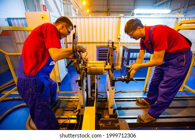 Atyrau, Kazakhstan - May 21,2012: Flowserve Company Modern Plant. Restoration Parts For Oil And Gas Industry. Two Workers In Blue Coveralls And Red Polo Shirts Fixing Electric Motor Rotor.