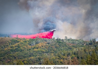 AUBURN, CA, U.S.A. - AUG. 5, 2021: Photo of a fire plane dropping red fire retardant on the Foresthill Fire, located in the Sierra Nevada foothills, California, near Auburn.