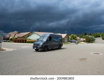 AUBURN, CA, U.S.A. - MAY 18, 2020: An Amazon delivery van drives up the street of a suburban neighborhood with huge storm clouds in the sky.