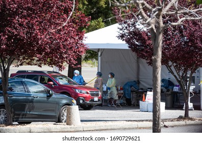 AUBURN, CA/U.S.A. - APRIL 1, 2020: Photo of a tented drive-through COVID19 testing area with masked healthcare workers and red Subaru in the parking lot of Sutter Auburn Faith Hospital.  