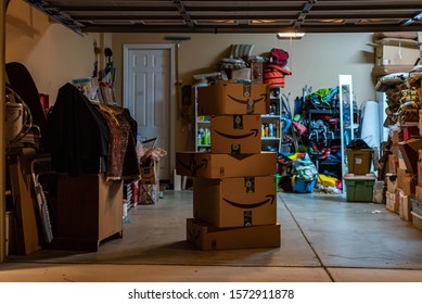 AUBURN, CA/U.S.A. - NOVEMBER 27, 2019: A stack of Amazon boxes sits in a garage in Northern California at night.  Amazon can now deliver orders inside customers' garages with an Amazon key.