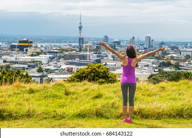 Auckland city skyline view from Mount Eden of Sky tower, New Zealand. Happy woman with arms up in freedom and happiness at top of Mt Eden urban park famous tourist attraction.