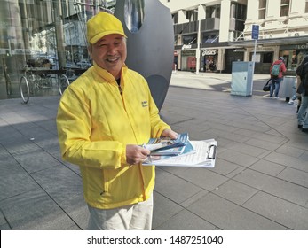 Auckland / New Zealand - August 24 2019: View Of Falun Gong (Dafa) Man In Yellow Jacked Distributing Brochures In Queen Street