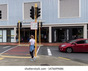 Auckland / New Zealand - August 7 2019: View Of Young Woman Crossing Road At Traffic Light Before Entering Britomart Railway Station In Downtown Auckland