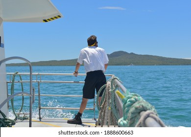 Auckland, New Zealand - January 5, 2021: View of crew member (deckhand) on board Fullers ferry with Rangitoto Island in background