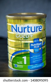 Auckland, New Zealand - May 22 2019: Tin Of Heinz Nurture Gold Plus Cows Milk Formula For Infants From Birth. 900gm Tin With Gold Lid. Gold Coloured Tin On Dark Kitchen Bench With Grey Background.