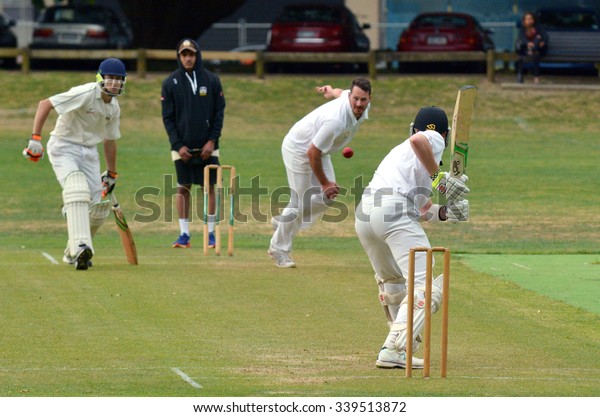 AUCKLAND - NOV 14 2015:Young adult men playing\
Cricket in Victoria park Auckland, New Zealand.Cricket is played by\
120 million players in many countries, making it the world\'s 2nd\
most popular sport.