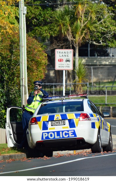 AUCKLAND,NZ - JUNE 03 2014:Traffic Police\
officer pointing his radar gun at speeding traffic.Traffic Police\
Monitor traffic to ensure motorists observe traffic regulations and\
safe driving\
procedures.