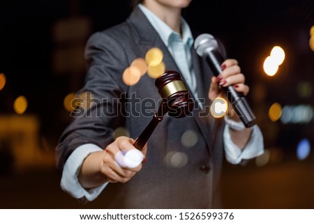 The auctioneer conducts the auction with a microphone on blurred background.