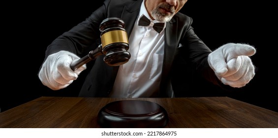 Auctioneer, salesperson with gavel at public auction. Senior male barker in formal elegant suit with auction hammer for close the bidding. - Shutterstock ID 2217864975