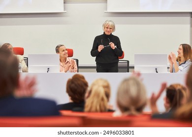 Audience applauding for female speaker on podium during business conference in convention center - Powered by Shutterstock