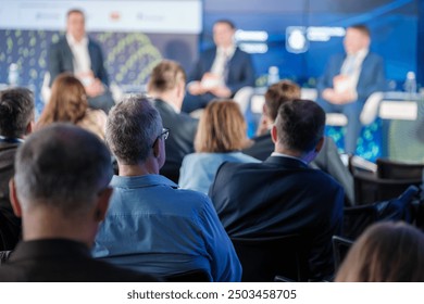 Audience attentively watching a business panel discussion during a professional conference. Engaged participants viewing speakers on stage. - Powered by Shutterstock