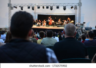 Audience In Front Of Small Stage Gathering In An Open Garden