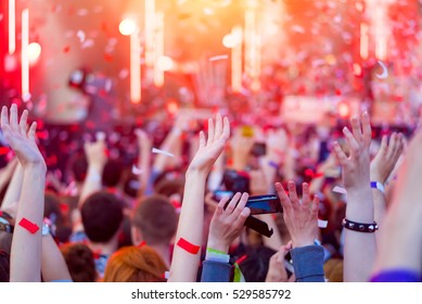 Audience with hands in the air at summer music festival. Fun concert party disco with blurred light background. Hands in the crowd at music festival. Night entertainment, music, happy, summer party