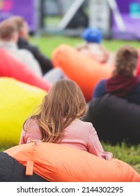 Audience At The Open Air Venue Listens To Lecturer, People On A Bean Bags Together Listen To Speaker On Stage At Master-class, Corporate Business Seminar Outdoors
