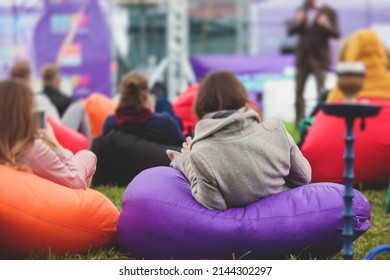 Audience At The Open Air Venue Listens To Lecturer, People On A Bean Bags Together Listen To Speaker On Stage At Master-class, Corporate Business Seminar Outdoors
