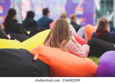 Audience At The Open Air Venue Listens To Lecturer, People On A Bean Bags Together Listen To Speaker On Stage At Master-class, Corporate Business Seminar Outdoors
