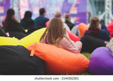 Audience At The Open Air Venue Listens To Lecturer, People On A Bean Bags Together Listen To Speaker On Stage At Master-class, Corporate Business Seminar Outdoors
