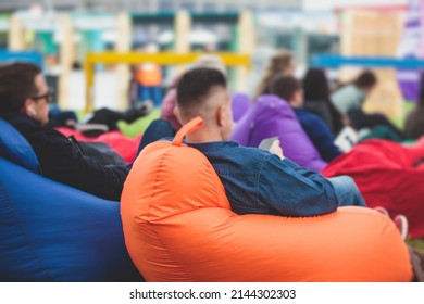 Audience At The Open Air Venue Listens To Lecturer, People On A Bean Bags Together Listen To Speaker On Stage At Master-class, Corporate Business Seminar Outdoors
