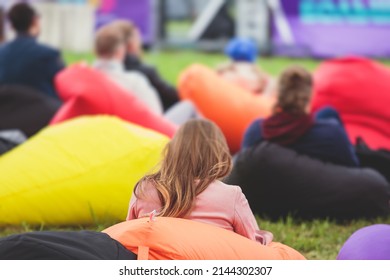 Audience At The Open Air Venue Listens To Lecturer, People On A Bean Bags Together Listen To Speaker On Stage At Master-class, Corporate Business Seminar Outdoors
