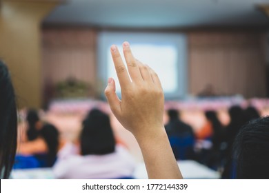 Audience Raising Hand While Speaker On Stage At Conference To Answer Question While Speaker Speech At Seminar Hall With Crowd Groups In Business And Education Concept