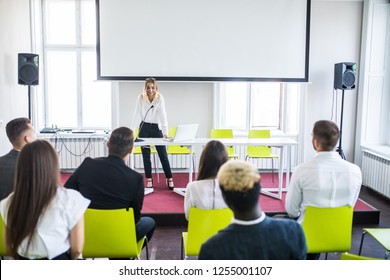 Audience raising hands up while businesswoman is speaking in training at the office. - Shutterstock ID 1255001107