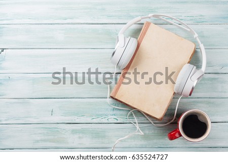 Audio book concept. Headphones, coffee and book over wooden table. Top view with space for your text