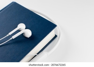 Audio Book Concept. Headphones And Book Over White Background. Closeup. Copy Space.