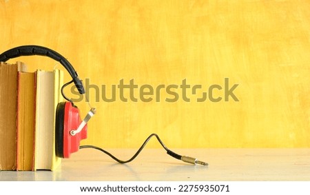 audio book concept with row of books,and vintage headphones,yellow background, free copy space